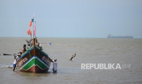 Sejumlah nelayan terpaksa mendorong perahu akibat dangkalnya air laut di perairan Serang, Banten, Rabu (27/4).  (Republika/Raisan Al Farisi)