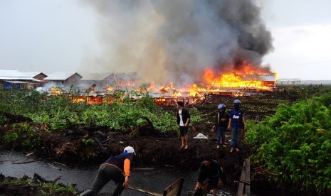 Sejumlah orang berlari meninggalkan lokasi permukiman warga eks-Gafatar yang dibakar massa di kawasan Monton Panjang, Dusun Pangsuma, Desa Antibar, Mempawah Timur, Kabupaten Mempawah, Kalbar, Selasa (19/1). (Antara/Jessica Helena Wuysang)