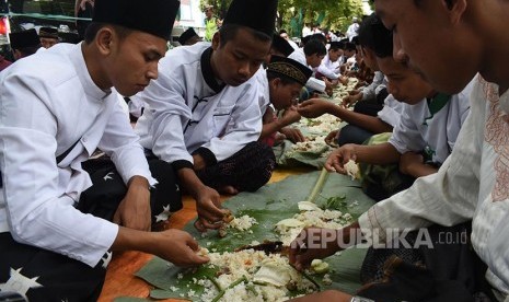 Sejumlah orang makan bersama ala pesanten saat peringatan Hari Santri 2016 di Magetan, Jawa Timur, Sabtu (22/10). Ribuan santri mengikuti istighatsah dan apel dilanjutkan makan bersama beralaskan daun pisang untuk memperingati hari santri.