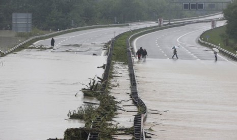   Sejumlah orang melintasi jalan bebas hambatan yang terpotong arus banjir di Grabenstaett dekat Traunstein, Jerman, Senin (3/6) waktu setempat.    (AP/Matthias Schrader)