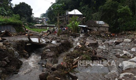 Sejumlah orang membersihkan material yang terbawa banjir bandang aliran lereng Gunung Lawu di Ngancar, Plaosan, Magetan, Jawa Timur, Senin (10/10).