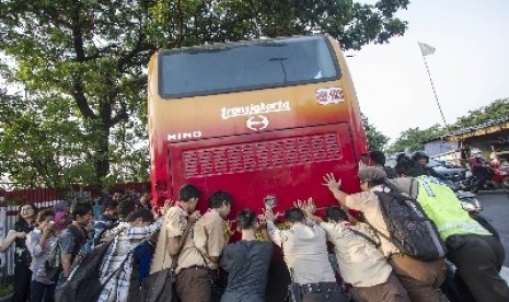   Sejumlah orang mendorong Bus Transjakarta yang mogok di kawasan Manggarai, Jakarta, Jumat (13/3).