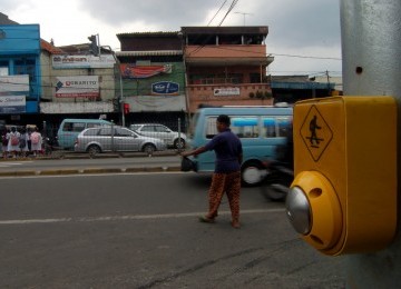 Sejumlah orang menyeberang jalan dengan menggunakan tombol penyeberangan dilampu merah kawasan Pasar Jatinegara, Jakarta Timur, Senin (6/2).(Republika/Prayogi)