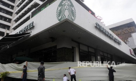 Sejumlah petugas membentangkan plastik untuk menutupi Starbuck Coffee yang terkena ledakan bom di jalan Thamrin, Jakarta, Kamis (14/1). (Republika/Darmawan)