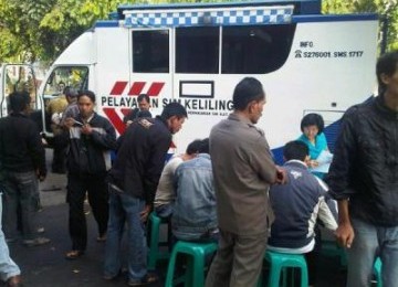 Sejumlah orang sedang sibuk mempersiapkan syarat-syarat untuk mengurus perpanjangan SIM dan STNK di mobil pelayanan keliling.