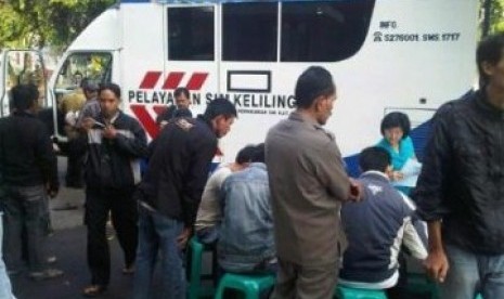 Sejumlah orang sedang sibuk mempersiapkan syarat-syarat untuk mengurus perpanjangan SIM dan STNK di mobil pelayanan keliling.