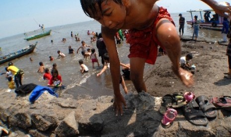 Sejumlah orang tua dan anak-anak berenang di tepian pantai wisata Tanjung Pasir, Kabupaten Tangerang, Banten