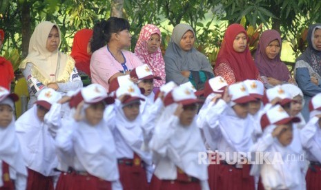 Sejumlah orang tua mendampingi anaknya yang mengikuti upacara bendera di SDN Kowel 3, Pamekasan, Jawa Timur, Senin (17/7).