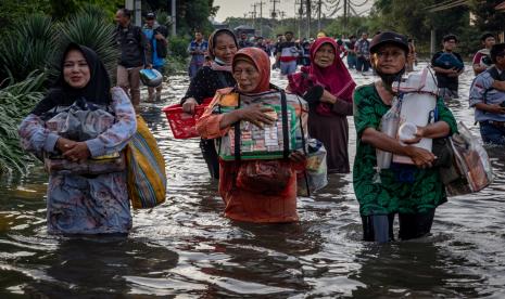 Sejumlah pedagang asongan pelabuhan berjalan menembus banjir limpasan air laut ke daratan atau rob yang merendam kawasan Pelabuhan Tanjung Emas Semarang, Jawa Tengah, Senin (23/5/2022). Banjir rob dengan ketinggian bervariasi hingga mencapai 1,5 meter itu disebabkan oleh tingginya pasang air laut serta adanya tanggul yang jebol di kawasan tersebut, sementara itu personel dari Basarnas, TNI-Polri dan relawan diterjunkan untuk membantu evakuasi para pekerja maupun warga. 