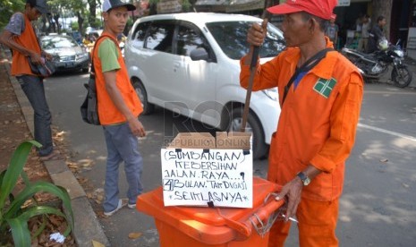   Sejumlah pekerja harian lepas (PHL) Dinas kebersihan DKI Jakarta meminta sumbangan kepada para pengendara yang melintas di kawasan Rawamangun, Jakarta Timur, Kamis (17/4). (Republika/Rakhmawaty La'lang)