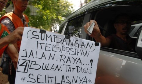   Sejumlah pekerja harian lepas (PHL) Dinas kebersihan DKI Jakarta meminta sumbangan kepada para pengendara yang melintas di kawasan Rawamangun, Jakarta Timur, Kamis (17/4). (Republika/Rakhmawaty La'lang)