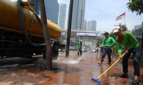 Sejumlah pekerja membersihkan lumpur sisa banjir di pedestrian jalan protokol Sudirman, Jakarta Pusat, Sabtu (19/1). (Republika/Agung Fatma Putra)