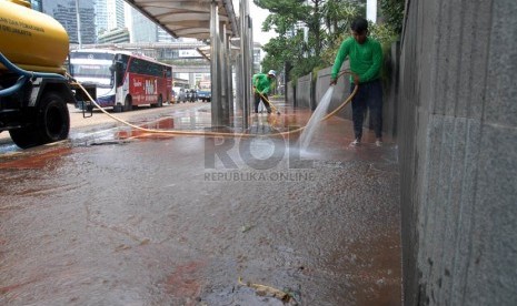 Sejumlah pekerja membersihkan lumpur sisa banjir di pedestrian jalan protokol Sudirman, Jakarta Pusat, Sabtu (19/1). (Republika/Agung Fatma Putra)