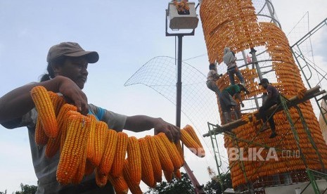 Sejumlah pekerja menata jagung saat proses pendirian menara jagung di Komplek Perkantoran Terpadu Kabupaten Boyolali, Jawa Tengah, Jumat (21/10). Menara setinggi 15 meter yang membutuhkan sebanyak 18.000 bonggol jagung tersebut akan digunakan sebagai ikon 