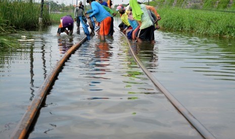 Sejumlah pekerja mengerjakan perbaikan bantaran rel kereta api yang terendam di kawasan Porong, Sidoarjo, Jawa Timur, Rabu (17/2).