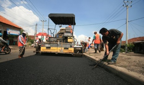 Sejumlah pekerja menggunakan alat berat melakukan pelapisan aspal di jalur pantura Lohbener, Indramayu, Jawa Barat, 