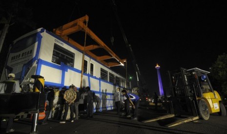  Sejumlah pekerja menurunkan gerbong monorail di halaman Lapangan Monas, Jakarta, Sabtu (8/6) dini hari.  (Antara/Zabur Karuru)