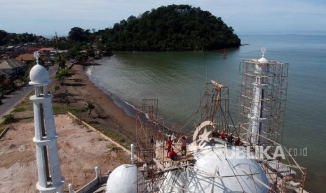 Sejumlah pekerja menyelesaikan pembangunan kubah masjid, di Pantai Padang, Sumatera Barat, Ahad (9/12/2018).