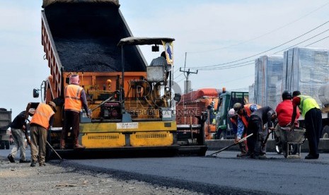   Sejumlah pekerja menyelesaikan perbaikan jalan di jalur pantura wilayah Indramayu, Jawa Barat.