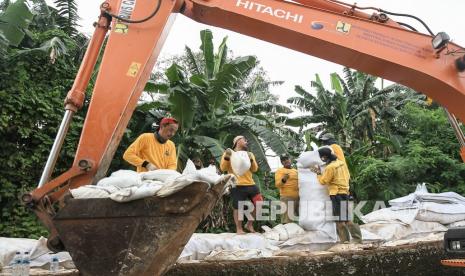 Sejumlah pekerja menyusun karung berisi pasir untuk tanggul sementara di aliran kali Cakung di Jatiasih, Bekasi, Jawa Barat, Kamis (4/11/2021). Dinas Bina Marga dan Sumber Daya Air (DBMSDA) Bekasi membuat tanggul sementara aliran kali Cakung yang jebol pada (2/11) dengan karung pasir untuk mencegah luapan air kali yang menyebabkan banjir.