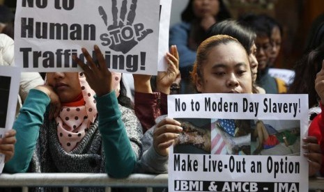   Sejumlah pekerja migran membawa foto pekerja asal Indonesia Erwiana Sulistyaningsih, saat berunjuk rasa di luar gedung Konsulat Indonesia di Hong Kong, Kamis (16/1).  (AP/Kin Cheung)