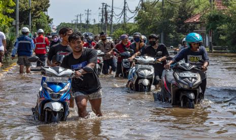 Sejumlah pekerja pelabuhan mendorong motor mereka yang mogok saat menerobos banjir limpasan air laut ke daratan atau rob yang merendam kawasan Pelabuhan Tanjung Emas, Semarang, Jawa Tengah, Selasa (24/5/2022). Sejumlah aktivitas pelabuhan maupun industri di kawasan tersebut masih lumpuh akibat peristiwa banjir rob sejak Senin (23/5) kemarin yang hingga pada Selasa (24/5) pukul 13:30 masih merendam beberapa titik kawasan pelabuhan dengan ketinggian bervariasi hingga mencapai satu meter.