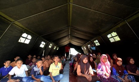 Sejumlah pelajar Madrasah Ibtidaiyah Negeri (MIN) mengikuti proses belajar mengajar di tenda darurat pasca sekolah mereka roboh akibat gempa 6,5 SR di Desa Paru Keude, Kecamatan Bandar Baro, Pidie Jaya, Aceh, Jumat (16/12). 