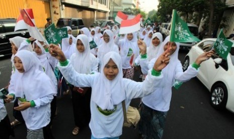 Sejumlah pelajar melambaikan bendera NU saat mengikuti jalan santai di Surabaya, Jawa Timur, Ahad  (18/10).