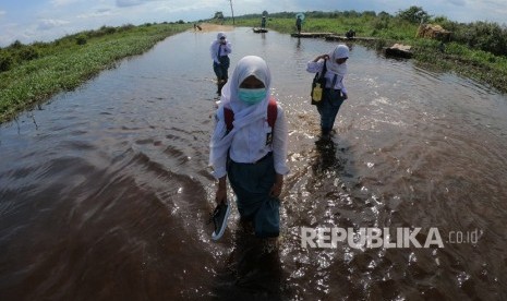 Sejumlah pelajar melewati jalan yang terendam banjir. Masyarakat diimbau siaga menghadapi curah hujan tinggi karena berpotensi bencana alam. Ilustrasi.