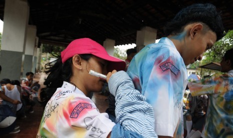 Sejumlah pelajar mencorat-coret baju seragam sekolah mereka seusai mengikuti Ujian Nasional tingkat SMK di Depok, Jawa Barat, Kamis (7/4). 