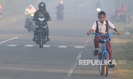 Sejumlah pelajar menembus kabut asap saat menuju ke sekolah mereka di kawasan jalan Desa Suak Timah, Samatiga, Aceh Barat, Aceh, Selasa (30/7/2019).