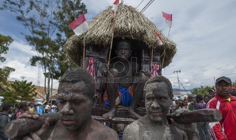  Sejumlah pelajar mengangkat replika Honai (rumah adat Papua) ketika mengikuti acara karnaval keliling kota di kota Wamena, Jayawijaya, Papua.