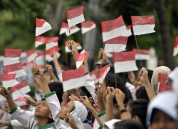 Sejumlah pelajar sekolah dasar (SD) melambaikan bendera saat menyambut perarakan api obor Sea Games XXVI di Jakarta, Jumat (4/11). 