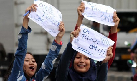 Sejumlah pelajar sekolah menuliskan pesan Om Telolet Om agar pengemudi bus membunyikan klakson di Jalan Sudirman, Bekasi, Jawa Barat, Rabu (21/12). 