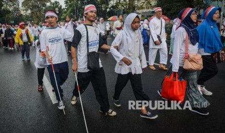  Sejumlah pelajar tuna netra mengikuti jalan santai dengan tema Jalan Sehati menuju Lapangan Gasibu, Kota Bandung, Jawa Barat, Senin (12/12). 