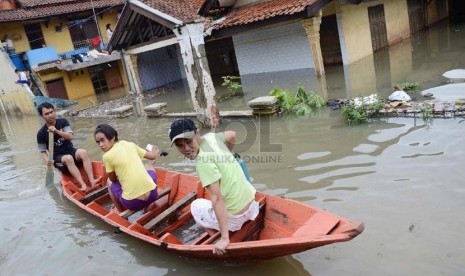 Sejumlah penduduk melintasi Jl Cieunteung, Kecamatan Baleendah, Kabupaten Bandung, yang sudah terendam Banjir, Ahad (15/12).  (Republika/Edi Yusuf)