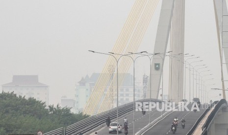 Sejumlah pengendara kendaraan bermotor melintas di atas jembatan Siak IV yang diselimuti kabut asap dampak kebakaran hutan dan lahan, di Pekanbaru, Riau, Selasa (6/8/2019). 