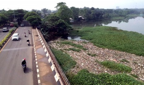 Sejumlah pengendara kendaraan melintas di dekat Situ Pengarengan yang dipenuhi sampah dan gulma eceng gondok di Jalan Juanda, Depok, Jawa Barat, Senin (6/5/2019).