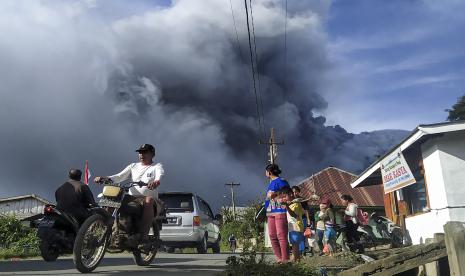 Sejumlah pengendara melintas di Jalan Karo-Langkat dengan latar belakang Gunung Sinabung yang menyemburkan material vulkanik di Desa Kutarayat, Naman Teran, Karo, Sumatera Utara, Kamis (13/8/2020). Pusat Vulkanologi dan Mitigasi Bencana Geologi (PVMBG) menyatakan Gunung Sinabung berstatus level III atau siaga dan meminta masyarakat untuk tidak melakukan aktivitas di desa yang telah direlokasi.