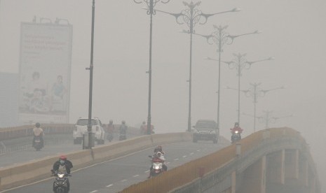 Sejumlah pengendara melintas di jalan yang dipenenuhi kabut asap kebakaran hutan dan lahan di Pekanbaru, Riau, Rabu (30/9). 