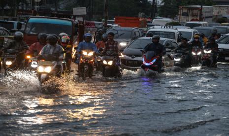 Sejumlah pengendara melintasi genangan air di Jalan Arif Rahman Hakim, Depok, Jawa Barat, Rabu (19/10/2022). Hujan deras serta buruknya sistem drainase di kawasan tersebut menyebabkan jalan raya tergenang air setinggi 50cm dan berimbas kepada kemacetan panjang. 