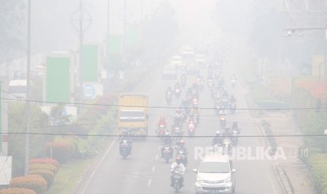 Sejumlah pengendara melintasi jalan yang diselimuti kabut asap di Pontianak, Kalimantan Barat, Senin (16/9/2019).