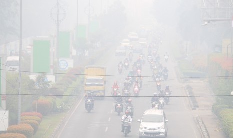 Sejumlah pengendara melintasi jalan yang diselimuti kabut asap di Pontianak, Kalimantan Barat, Senin (16/9/2019).