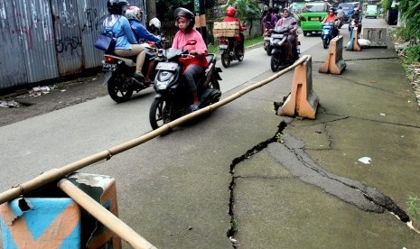 Sejumlah pengendara melintasi jalan yang longsor di Jalan Raya Cilebut, Sukaraja, Kabupaten Bogor, Jawa Barat, Jum'at (11/3).