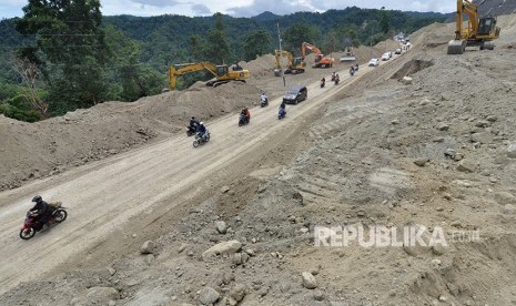 Sejumlah pengendara melintasi lokasi proyek pembangunan dan peningkatan infastruktur pada jalur jalan nasional Trans Sulawesi yang masuk ke dalam Proyek Strategis Nasional (PSN) di Kawasan Pegunungan Kebun Kopi, Sulawesi Tengah, Senin (14/5).