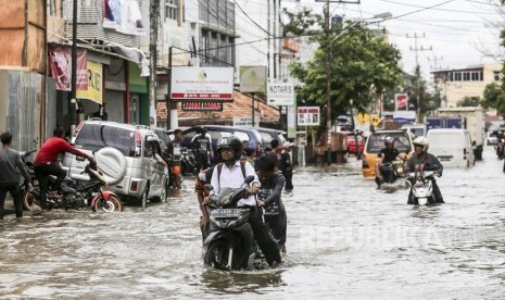 Sejumlah pengendara mendorong kendaraannya saat melintasi jalan yang terendam banjir dikawasan Sekip Bendung, Palembang, Sumatera Selatan, Selasa (13/11/2018). 