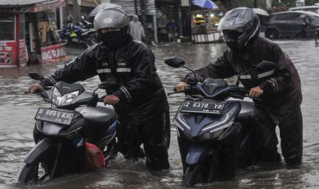 Sejumlah pengendara mendorong motornya saat melintasi banjir. Badan Meteorologi Klimatologi dan Geofisika (BMKG) memprediksi potensi cuaca ekstrem akan terus berlangsung di Indonesia hingga pergantian tahun. Komunitas Peduli Sungai Cileungsi Cikeas (KP2C) memberikan imbauan terkait adanya potensi banjir di tengah cuaca ekstrem ini.