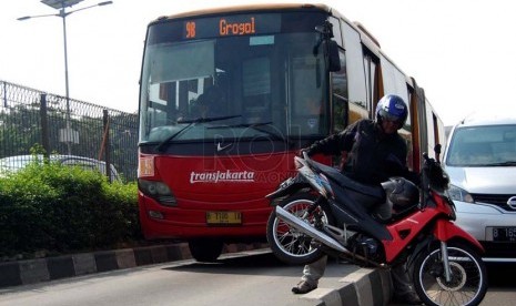 Sejumlah pengendara mengangkut motornya keluar dari jalur busway saat Polisi menggelar razia di jalan MT. Haryono, Jakarta Timur, Selasa (24/6).