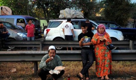   Sejumlah pengendara mobil berbuka puasa di pinggir jalan tol akibat terjebak kemacetan panjang di KM 57, Cikarang, Jawa Barat, Jumat (17/8).   (Prayogi)