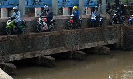 Sejumlah pengendara motor melintas di jalan setapak pintu air, Karawaci, Tangerang, Banten, Kamis (19/11).